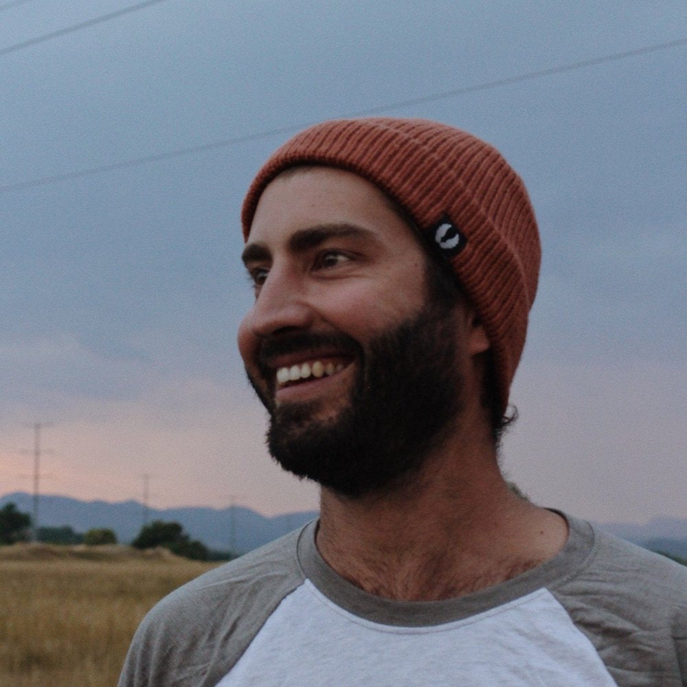 smiling man with beard wearing rust orange ahab knitted beanie 