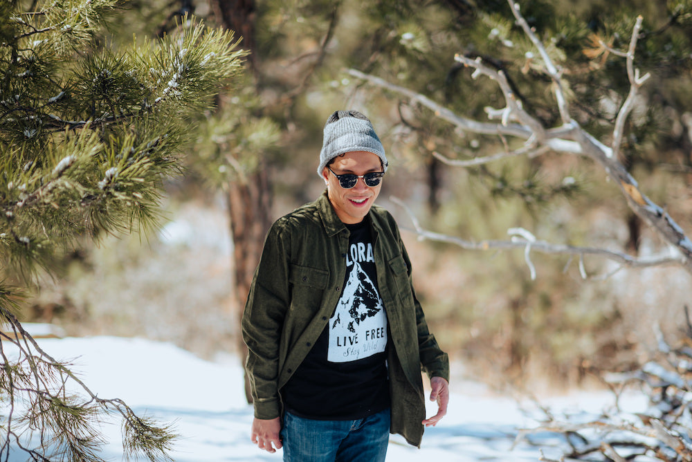 man wearing green flannel, colorado live free tee, and Jackson trio knitted beanie