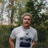 man outside wearing light spruce green ahab knitted beanie and light blue ascend mountain tee 