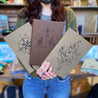 Find your path compass faux leather journal, speak for the trees dark brown faux leather journal, and 8% salty faux leather journal held by woman showing engraved journal covers.