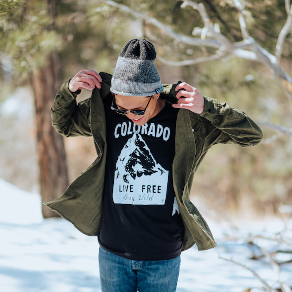 man wearing colorado live free stay wild black tee and green flannel