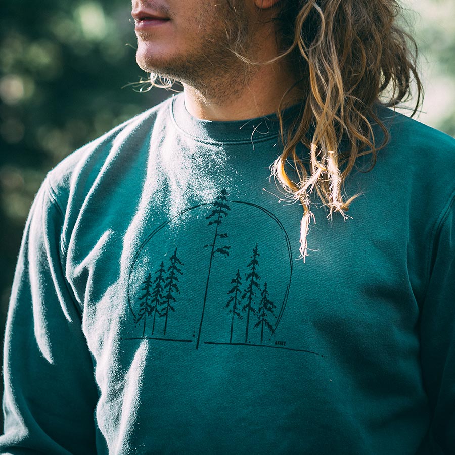 Close up of man wearing green sweatshirt with trees 