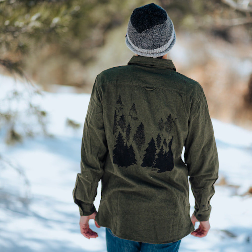 back of man wearing green flannel with trees